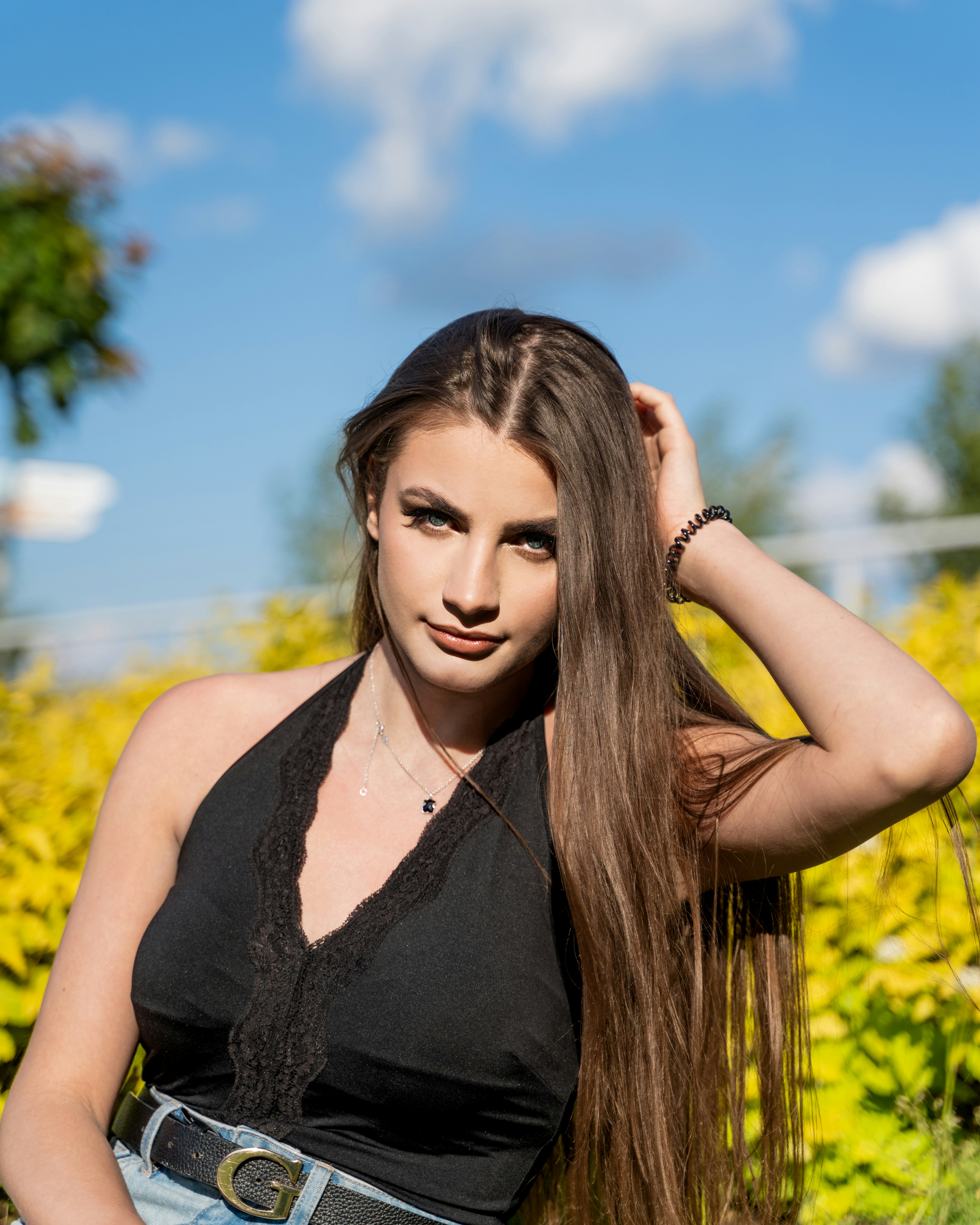 woman in black v neck shirt standing on yellow flower field during daytime